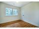 Bedroom with hardwood floors, white walls, and a window at 5312 Woodsdale Rd, Raleigh, NC 27606