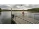 Picturesque view of a dock on a calm lake, featuring safety equipment and lush greenery in the background at 5312 Woodsdale Rd, Raleigh, NC 27606
