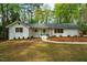 Charming single-story home with a white brick facade, a light blue front door, and well-maintained landscaping at 5312 Woodsdale Rd, Raleigh, NC 27606