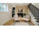 Cozy living space featuring a brick fireplace, staircase, and hardwood floors at 5312 Woodsdale Rd, Raleigh, NC 27606