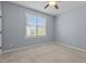 Cozy bedroom features neutral carpet, a ceiling fan, and a bright window with natural lighting at 5408 Colonial Oaks Dr, Apex, NC 27539