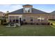 View of the house from the backyard showing a patio, grill, manicured lawn, and the screened-in back porch area at 5733 Mizuno Dr, Fuquay Varina, NC 27526