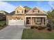Inviting two-story home with a two-car garage, a brick facade, and a covered front porch at 5733 Mizuno Dr, Fuquay Varina, NC 27526