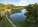 Aerial view showcases a scenic golf course with a tranquil lake and winding paths at 5733 Mizuno Dr, Fuquay Varina, NC 27526