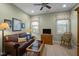 Cozy living room featuring a leather sofa, ceiling fan, and natural light from two windows at 5733 Mizuno Dr, Fuquay Varina, NC 27526