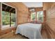 Cozy bedroom features wood walls, natural light from windows, and comfortable queen size bed at 605 Faucette Mill Rd, Hillsborough, NC 27278
