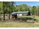 Large outbuilding and sheds surrounded by trees and a small garden at 605 Faucette Mill Rd, Hillsborough, NC 27278