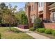 Brick townhouse showcasing a charming front porch and landscaped walkway, complemented by mature trees at 608 Derby Ct, Durham, NC 27707