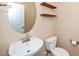 A view of the half bathroom featuring a pedestal sink and a round mirror at 617 Conover Rd, Durham, NC 27703