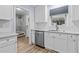 Bright kitchen showcasing white cabinetry, stainless steel dishwasher, and stylish wood flooring at 6568 English Oaks Dr, Raleigh, NC 27615