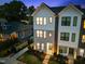 Two-story townhouse exterior featuring white siding, black framed windows, and professionally landscaped front yard at dusk at 700 W North St # 101, Raleigh, NC 27603