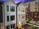 Modern, two-story home showcasing its bright exterior with black window trim and beautiful nighttime ambiance at 700 W North St # 101, Raleigh, NC 27603