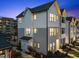 Two-story townhouse exterior featuring white siding, black framed windows, and manicured landscaping at dusk at 700 W North St # 101, Raleigh, NC 27603