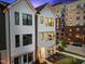 Modern townhouse exterior with white siding, black framed windows, and manicured landscaping at dusk at 700 W North St # 101, Raleigh, NC 27603