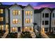 Charming townhouse exterior at dusk, featuring a white facade, black window frames, and landscaped front yard at 700 W North St # 101, Raleigh, NC 27603