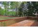 Backyard view showing a wooden deck surrounded by mature trees and a well-manicured lawn at 704 Voyager Pl, Durham, NC 27712