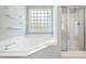 Bright bathroom with a soaking tub below a textured window and separate shower with glass door at 704 Voyager Pl, Durham, NC 27712