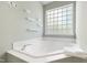 Bright bathroom features soaking tub below window and decorative shelves on the wall at 704 Voyager Pl, Durham, NC 27712