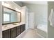 En-suite bathroom featuring double vanity, a large mirror, and a soaking tub at 704 Voyager Pl, Durham, NC 27712