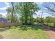 Expansive backyard with a wooden fence, lush grass, and mature trees at 730 Hopkins St, Durham, NC 27701