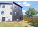 The rear exterior reveals a blend of black and white siding, enhanced by the privacy of a wooden fence, and lush greenery at 732 Hopkins St, Durham, NC 27701
