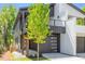Striking home with black and white siding, showcasing a covered porch, a balcony, and a contemporary garage door at 732 Hopkins St, Durham, NC 27701