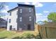 Back of modern two-story home features black and white siding, an enclosed backyard with a wood fence, and lush landscaping at 732 Hopkins St, Durham, NC 27701
