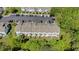 An aerial view of townhomes with garden plots, parking, and surrounded by mature trees at 7613 Satinwing Ln, Raleigh, NC 27617