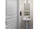 Powder room with a pedestal sink, white door, and a round mirror at 7613 Satinwing Ln, Raleigh, NC 27617