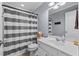 Bathroom with a white vanity, framed mirror and gray and white striped shower curtain at 7613 Satinwing Ln, Raleigh, NC 27617