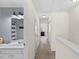 Hallway with white wainscoting leading to a bathroom with a gray and white striped shower curtain at 7613 Satinwing Ln, Raleigh, NC 27617