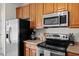 Kitchen with stainless steel appliances and wood cabinets featuring a refrigerator, oven and overhead microwave at 7613 Satinwing Ln, Raleigh, NC 27617