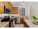 Close-up of kitchen showcasing stainless steel appliances, wood cabinets, and open layout with a view into the living area at 7613 Satinwing Ln, Raleigh, NC 27617