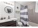 Bathroom featuring shiplap, tile, combination tub/shower and a round mirror at 7707 Falcon Rest Cir, Raleigh, NC 27615