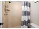 Tiled shower with adjustable shower head and a gray striped shower curtain at 7707 Falcon Rest Cir, Raleigh, NC 27615