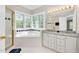 Bright bathroom featuring a soaking tub with window views and double vanity with granite countertops at 8309 Nantahala Dr, Raleigh, NC 27612