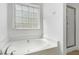 Soaking tub and glass shower in bathroom with window and white fixtures at 837 Varina Ln, Fuquay Varina, NC 27526