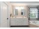 Bright bathroom featuring dual sinks with white cabinetry and a garden tub at 9225 Palm Bay Cir, Raleigh, NC 27617