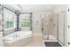 Bright bathroom with tub and shower, natural light and tile floor at 9225 Palm Bay Cir, Raleigh, NC 27617