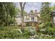 Lush backyard view with mature trees and flowering plants surrounding a two-story home and deck at 1005 W Lenoir St, Raleigh, NC 27603