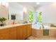 Bright bathroom featuring a soaking tub, marble countertops, and wood cabinets with ample storage space at 1011 Wood Sage Dr, Chapel Hill, NC 27516