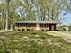 Single story brick home with manicured lawn and mature trees offers classic curb appeal at 1031 Jackson Royster Rd, Henderson, NC 27537
