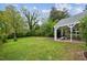 Large backyard with a covered patio, green grass, and mature trees at 1105 Englewood Ave, Durham, NC 27701