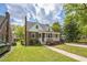 Charming brick home with a covered front porch, featuring dormer windows, under a bright, cloudy sky at 1105 Englewood Ave, Durham, NC 27701