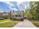 Charming brick home with a covered front porch and convenient carport, all under a bright, cloudy sky at 1105 Englewood Ave, Durham, NC 27701