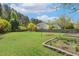 Large, well-manicured backyard with mature trees, garden beds, and a wooden fence at 1127 Woodlands Creek Way, Apex, NC 27502