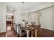 Dining area with views into kitchen, stylish chandelier, and seating for six with hardwood floors at 1127 Woodlands Creek Way, Apex, NC 27502