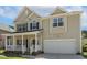 Traditional two-story home featuring a covered front porch and attached two-car garage at 1127 Woodlands Creek Way, Apex, NC 27502