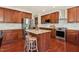 Spacious kitchen featuring stainless steel appliances, island, granite countertop, and rich wood cabinetry at 1127 Woodlands Creek Way, Apex, NC 27502