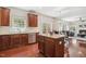 Kitchen with island, stainless steel appliances, hardwood floors, and a view of the dining and living areas at 1127 Woodlands Creek Way, Apex, NC 27502